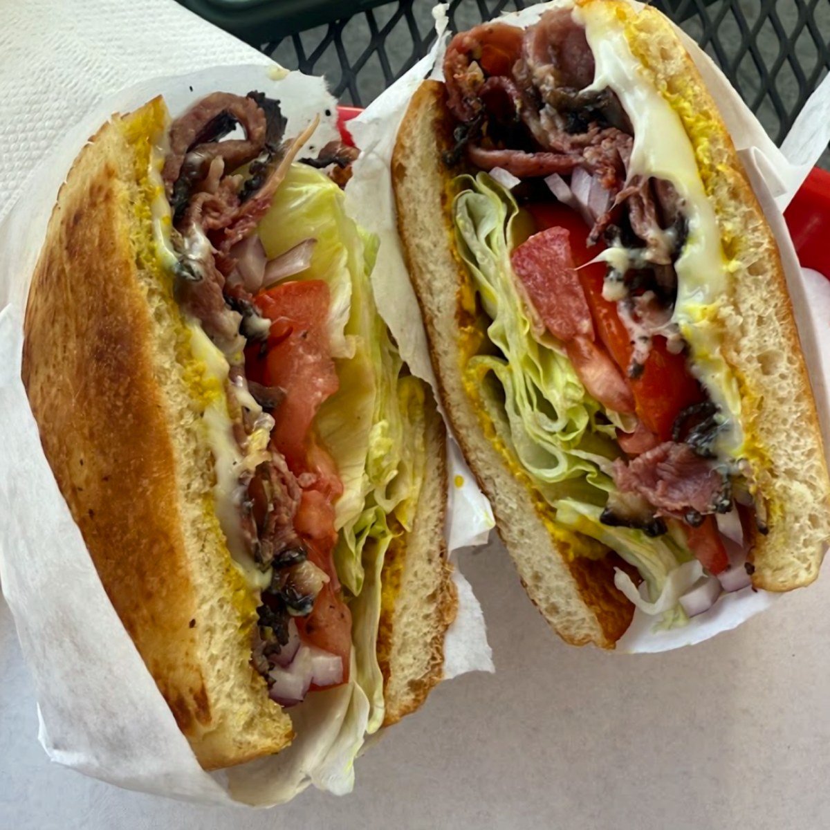 Pastrami sandwich with lettuce and tomato, cut in half